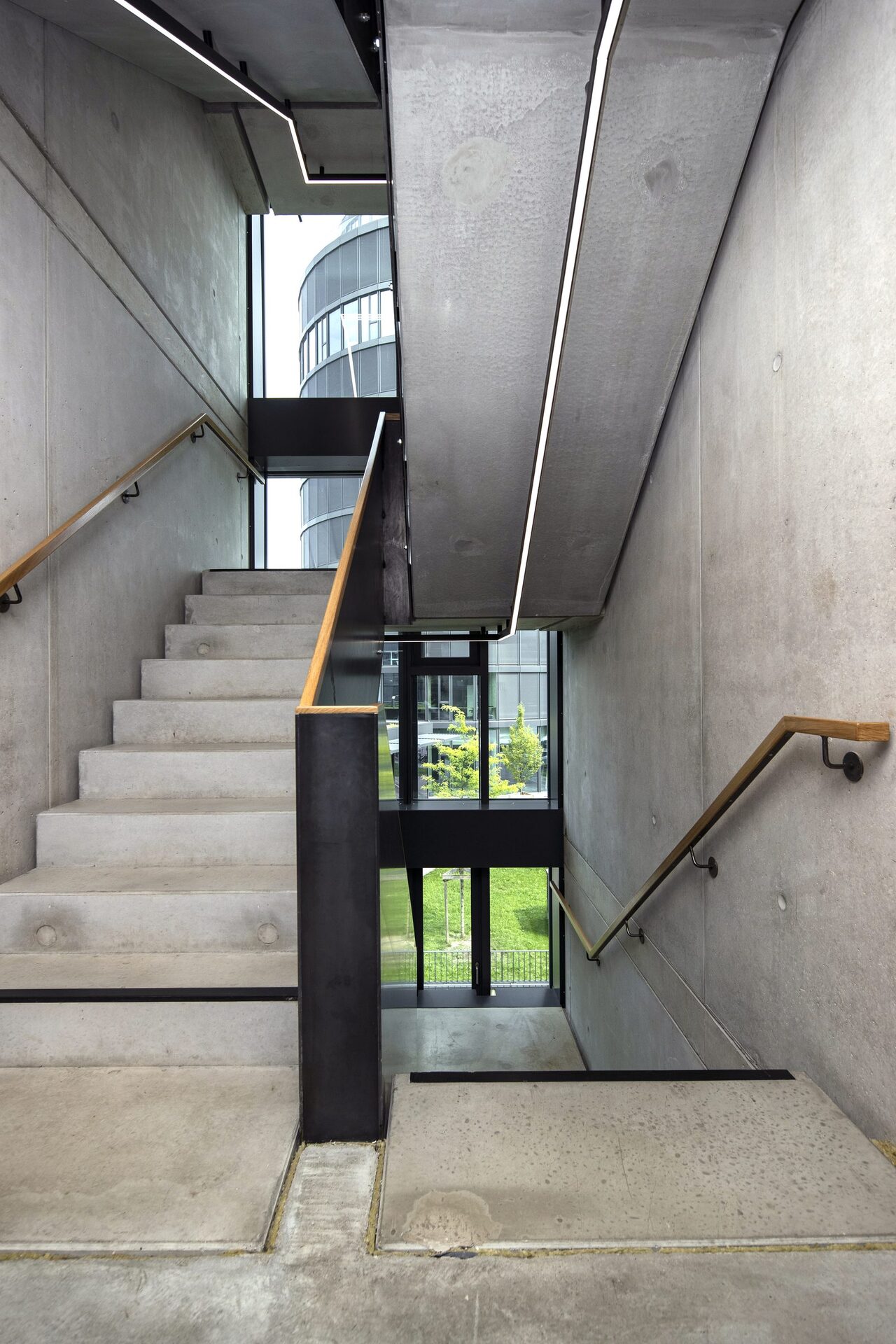Stairwell bar building · exposed concrete + wooden handrail, view of the tower
